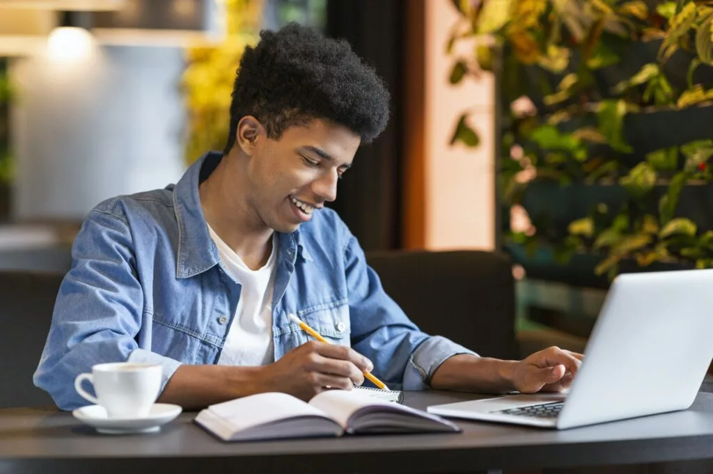 Successful african student working on project at cafeteria